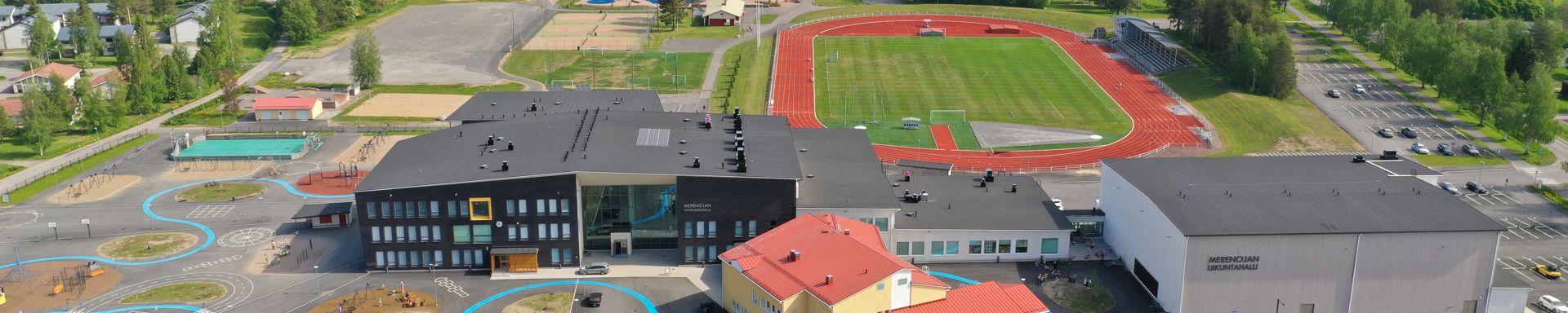 Koulurakennuksia ja taustalla urheilukenttä ja liikuntapaikkoja.