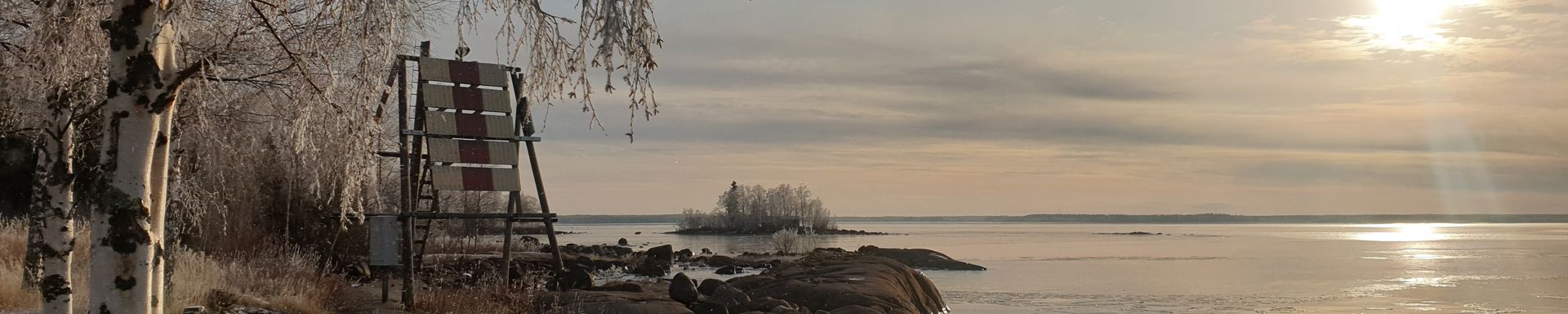 Kuvassa kivinen merenranta hämärässä ilta-auringossa