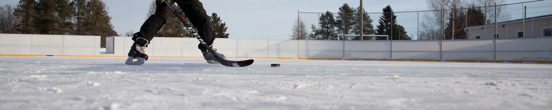 Luistelija, jolla maila ja kiekko ulkojäällä.