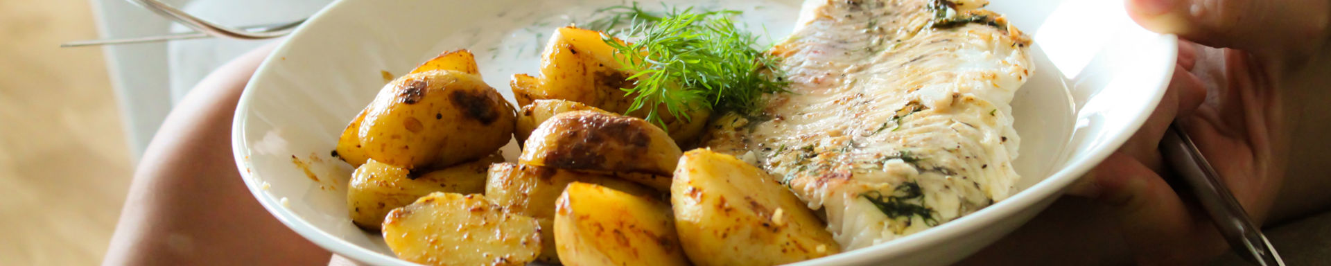 Ruoka, ruokalautanen, jossa perunoita ja kalaa.