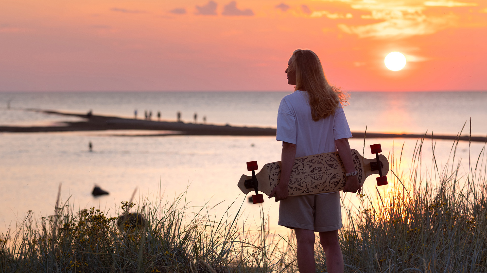 Nainen seisoo Kalajoen Hiekkasärkillä rullalaudan kanssa.