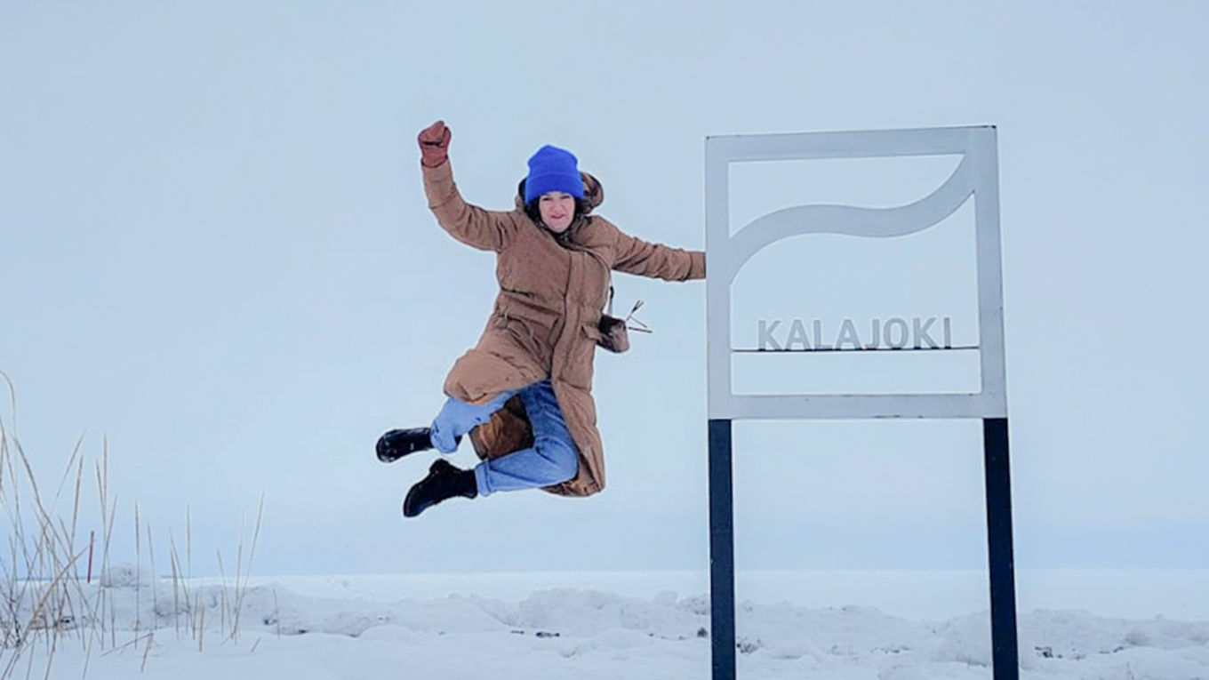 nainen hyppää ilmaan Kalajoki kyltin vieressä