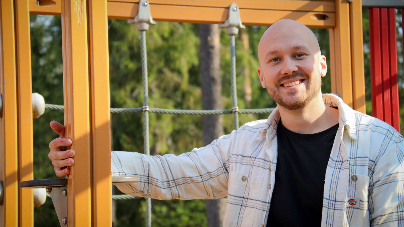 Atte Autio nojaa kiipeilytelineeseen ja hymyilee.