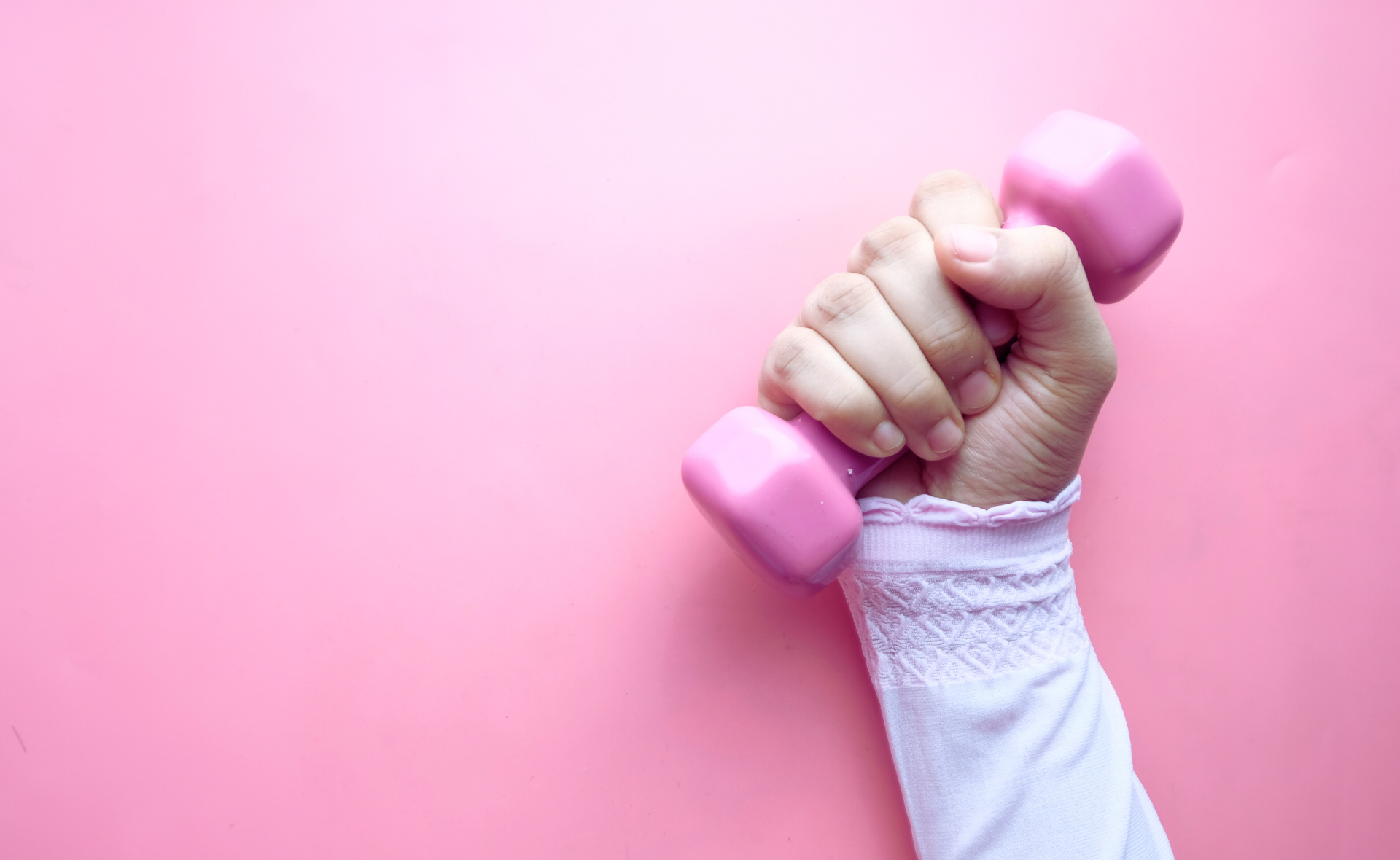 Käsi pitää vaaleanpunaista käsipainoa.
