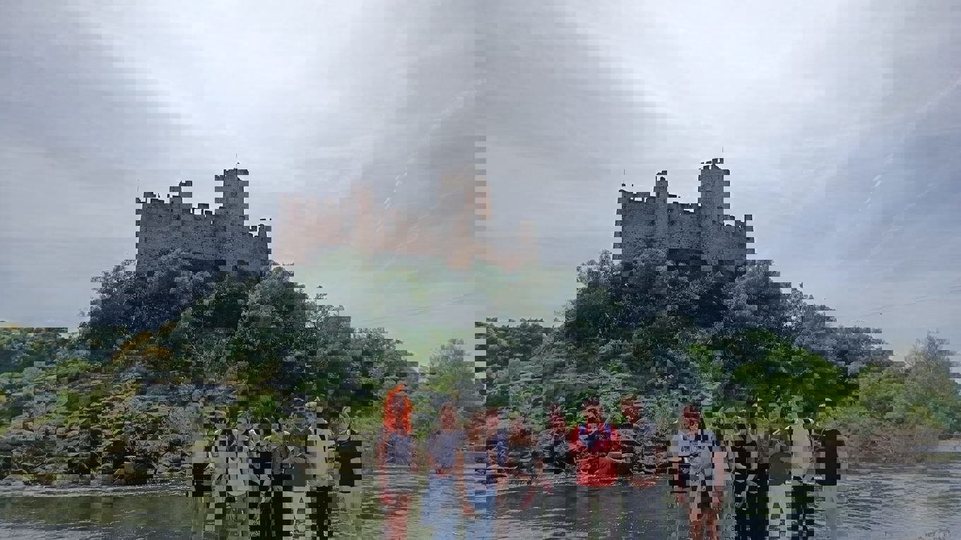 students in front of a castle over a river