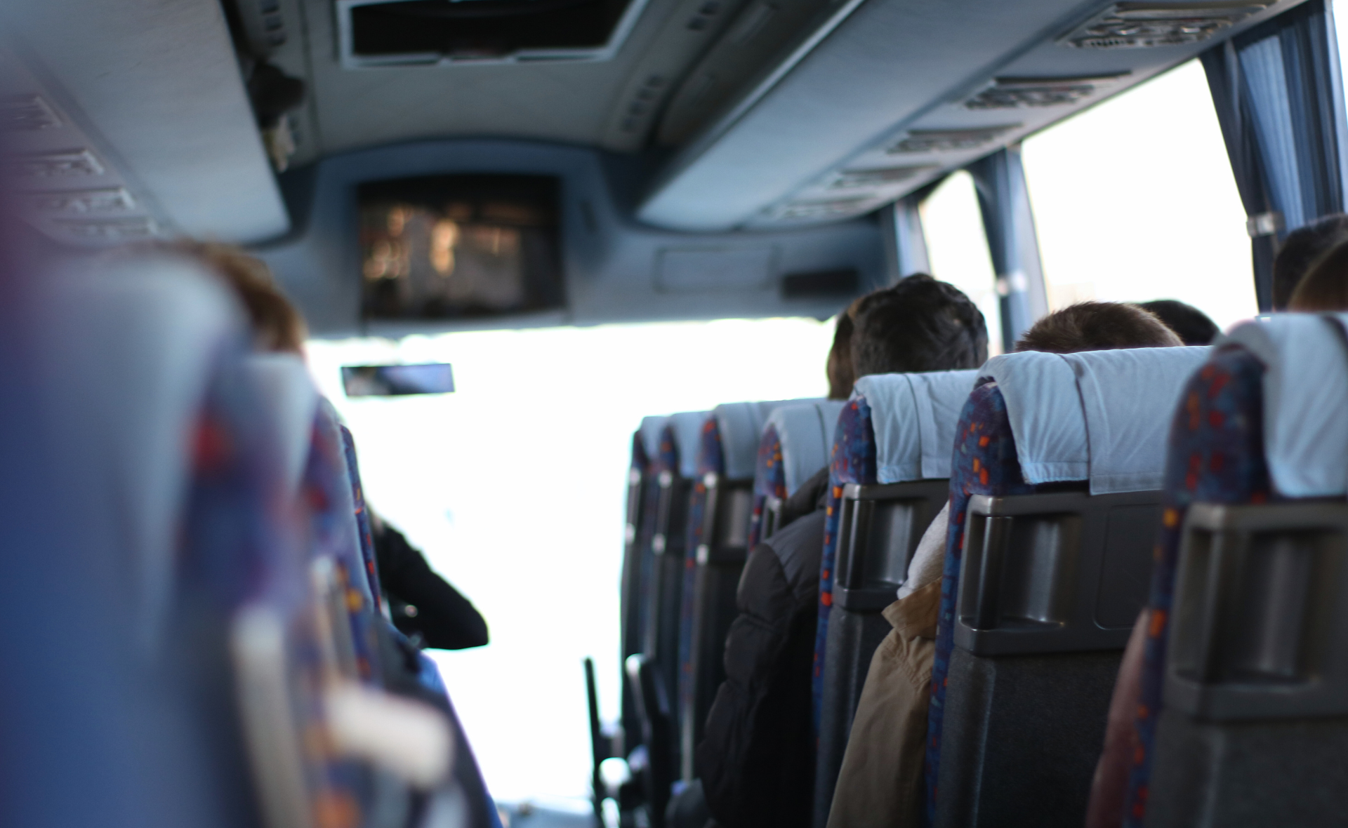 Linja-auton penkkejä ja matkustajia takaa kuvattuna.