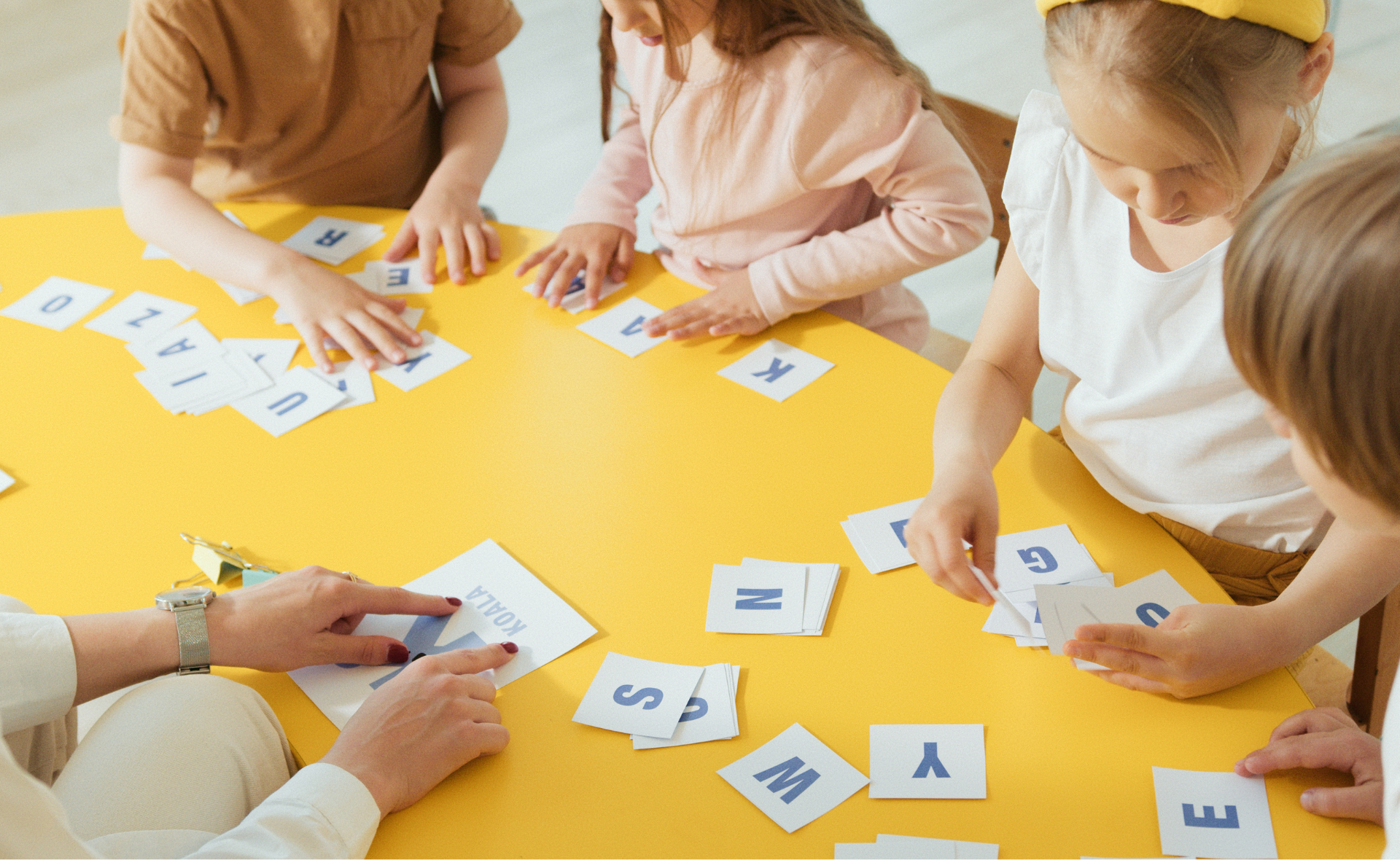 Lapsia pöydän äärellä pelaamassa kirjainpeliä.