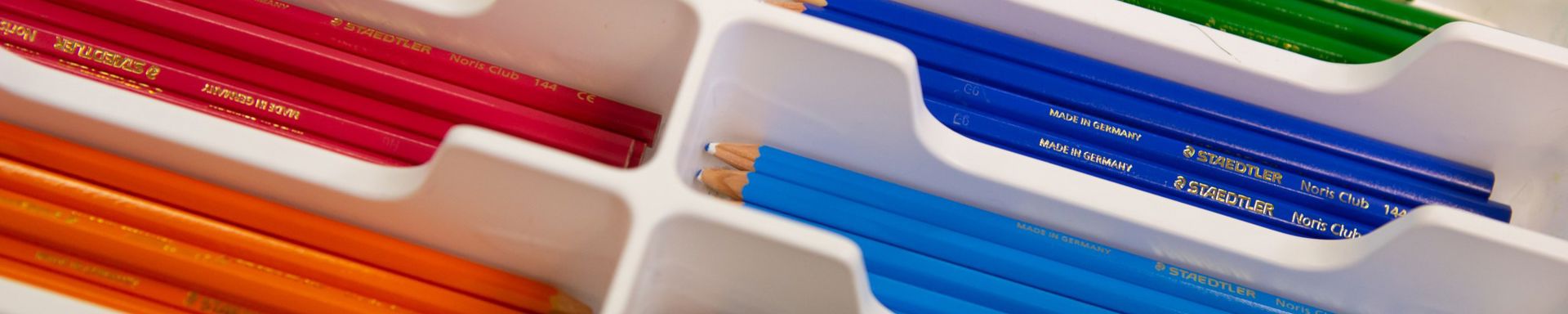 Eri värisiä kyniä lajiteltua kynälaatikkoon.