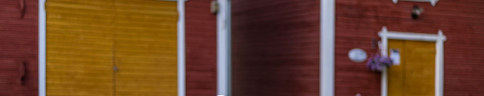 Vanha kaivo ja taustalla vanhoja aittoja.